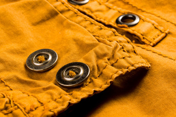 clothing items stonewashed cotton fabric texture with seams, clasps, buttons and rivets, macro
