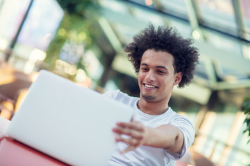 Victorious handsome man looking at his laptop while sitting in bright living room