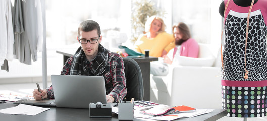 designer using laptop and graphics tablet to create sketches of new clothes