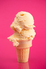 A Double Scoop Vanilla Ice Cream Cone on a Bright Pink Background