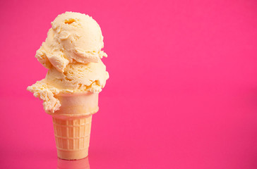 A Double Scoop Vanilla Ice Cream Cone on a Bright Pink Background