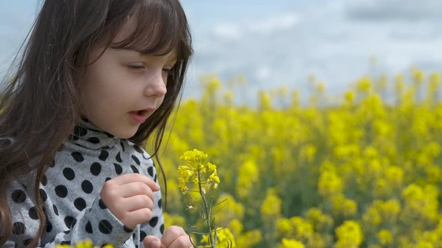 Adorable kid with flowers. Allergy to pollen. A cute little girl smells a flower in nature and reads.