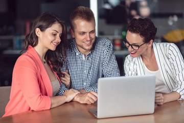 Investment adviser giving a presentation to a friendly smiling young couple seated at her desk in the office