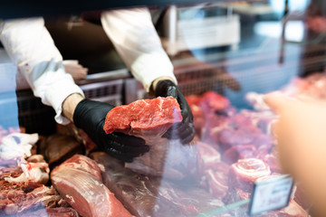Closeup on butcher's hands in gloves working in butchery. - 271156462