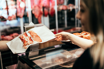 Woman buying fresh meat in butchery.