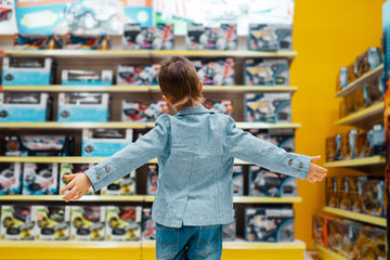 Little boy at the shelf in kids store, back view