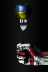A hand with a drawn England flag holds a fork, on which is a ball with a drawn Ukraine flag, a sign...