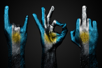 a set of three hands with a painted flag Argentina show middle finger, goat and Okay, a sign of aggression, protest and approval on a dark background.