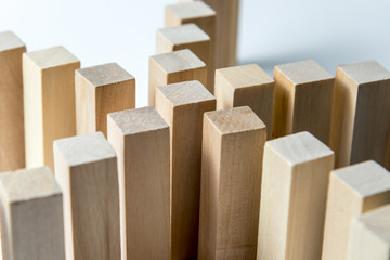 Many curved lines of wooden cubes are connected in the center into one, as a symbol of queues, a variety of tasks and a leader, on an uneven white background. Horizontal frame