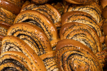 a lot of buns, popovers with poppy seeds lie one on another, cinnamon roll fresh pastries