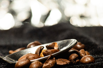 Grains of coffee on the spoon on the background of bokeh