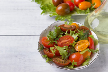 Fresh tomato and green salad in a plate on a wooden table ..
