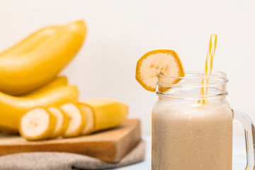 Delicious shake in cup with slices of fruit near bananas and cinnamon
