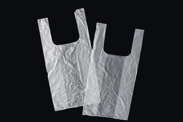 Plastic bag with handles, gloves, on a black background . Used plastic bag for recycling. Concept -...