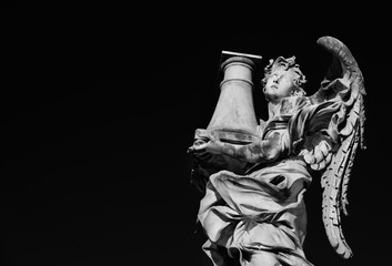 Angel statue holding the Column of Jesus Passion looks at the Heaven A 17th century baroque masterpiece at the top of Sant'Angelo Bridge in the center of Rome (Black and White with copy space)