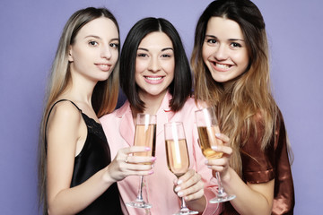 Fototapeta na wymiar three beautiful girls dressed in pajamas drink champagne and have fun