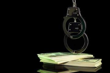 Handcuffs were hung on a dollar banknote in darkness background. Copy space for text or articles....