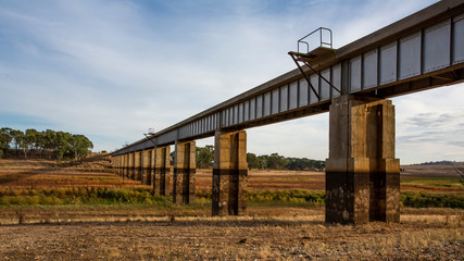 Diminishing perspective view of disused Railway Bridge over Joyces Creek its entry to Lake Cairn Curran on the Moolort Plains near Newstead, Victoria, Australia