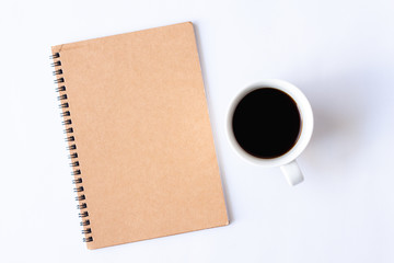 Top view notebook with cup of hot coffee on white background.
