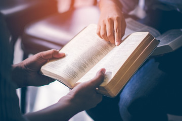 Male adults are reading the Holy bible by pointing to the character and to share the gospel to youth. The cross symbol, The books of the Bible, Concepts of Christianity. - obrazy, fototapety, plakaty