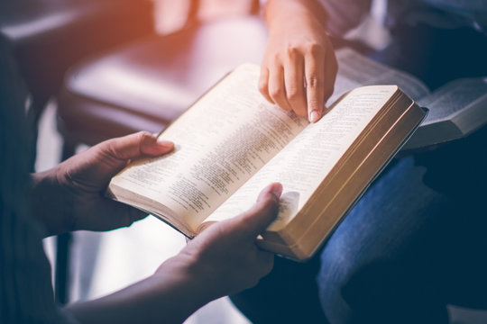 Male adults are reading the Holy bible by pointing to the character and to share the gospel to youth. The cross symbol, The books of the Bible, Concepts of Christianity.