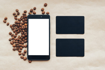 Mockup smartphone and blank business card on background with roasted coffee beans.