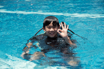 Young little Asian boy scuba diver showing ok hand signal, diving lessons for beginners.  Sign Language