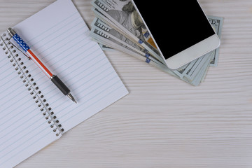 A pen and dollars banknote cash money in a notebook