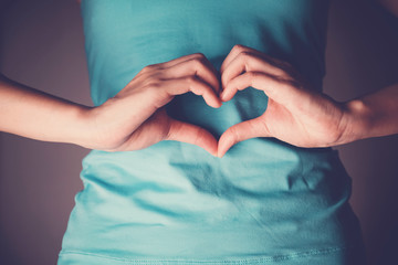 Woman hands making a heart shape on her stomach, healthy bowel degestion, probiotics  for gut health, leaky gut, Sign Language