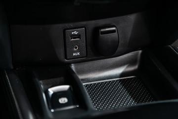 Сlose-up of the car  black interior:  power outlet 12V, USB, AUX and other buttons.