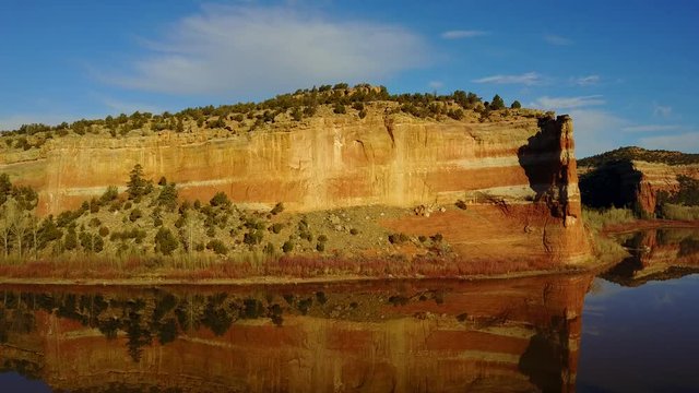 Ramah Lake in the Zuni Mountains of New Mexico, flanked with scubalpted red sand stone in early morning light.