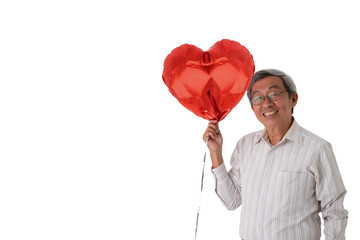 Old senior Asian man in white shirt holding a box of present and a heart shape ballon looking happy and loved, on isolated white background.