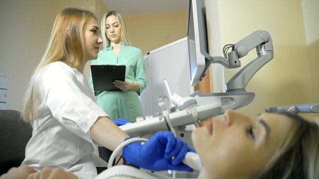 Doctor Taking A Sonogram Thyroid gland, nurse writes and helps the doctor