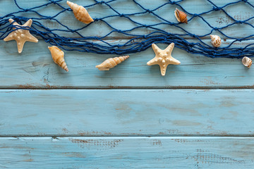 Summertime concept with sea rope, seashells and starfish on a blue wooden background. Top view. Free space for text.