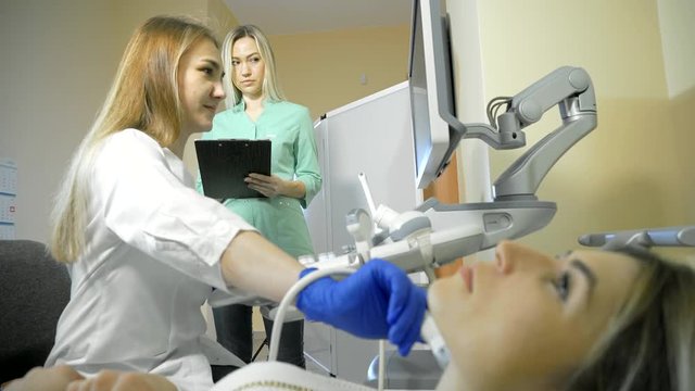 Doctor Taking A Sonogram Thyroid gland, nurse writes and helps the doctor