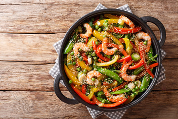 Vegetable stir fry with shrimps and sesame close-up in a frying pan. horizontal top view