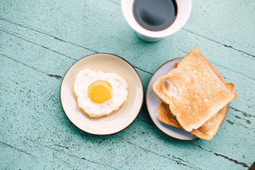 Fried eggs, toast, coffee, breakfast set placed on a blue wooden table