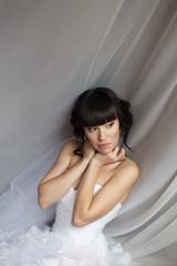 Naklejka premium Beauty portrait of bride wearing fashion wedding dress with feathers with luxury delight make-up and hairstyle, studio indoor photo. 