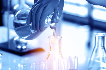 scientist with equipment and science experiments, laboratory glassware containing chemical liquid for research or analyzing a sample into test tube in laboratory