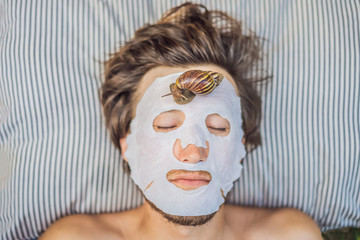 Young man makes a face mask with snail mucus. Snail crawling on a face mask. SPA for man, SPA for...
