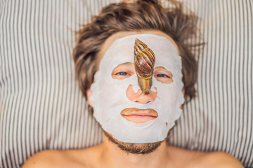 Young man makes a face mask with snail mucus. Snail crawling on a face mask. SPA for man, SPA for all