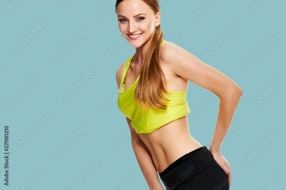 Wall mural picture of sporty woman checking her hips on blue color background