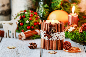 Candle decorated with cinnamon sticks. Christmas arrangement.