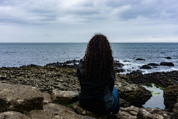 Girl is looking at the Atlantic Ocean on the Giant's Causeway in Northern Ireland