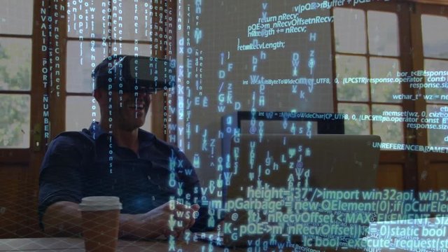 Man wearing virtual goggles while using a laptop