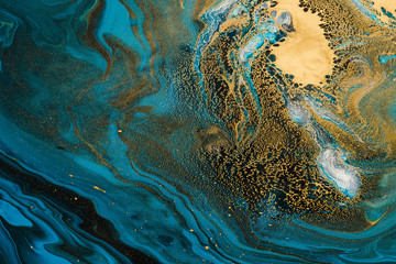 Acrylic Fluid Art. Blue waves and gold inclusion. Abstract stone background or texture