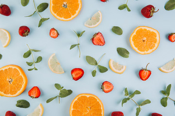 Summer colorful flat lay. Pattern made of citrus fruits, leaves and strawberries on the blue wooden table