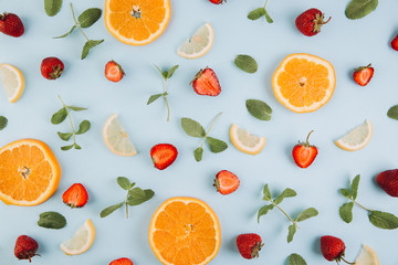 Summer colorful flat lay. Pattern made of citrus fruits, leaves and strawberries on the blue wooden table