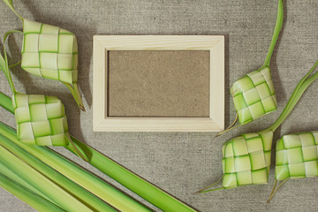 Ketupat (rice dumpling) with wooden frame on jute texture background. Ketupat is most popular food...