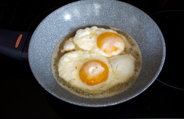 High angle view of the fried eggs in the pan on the stove